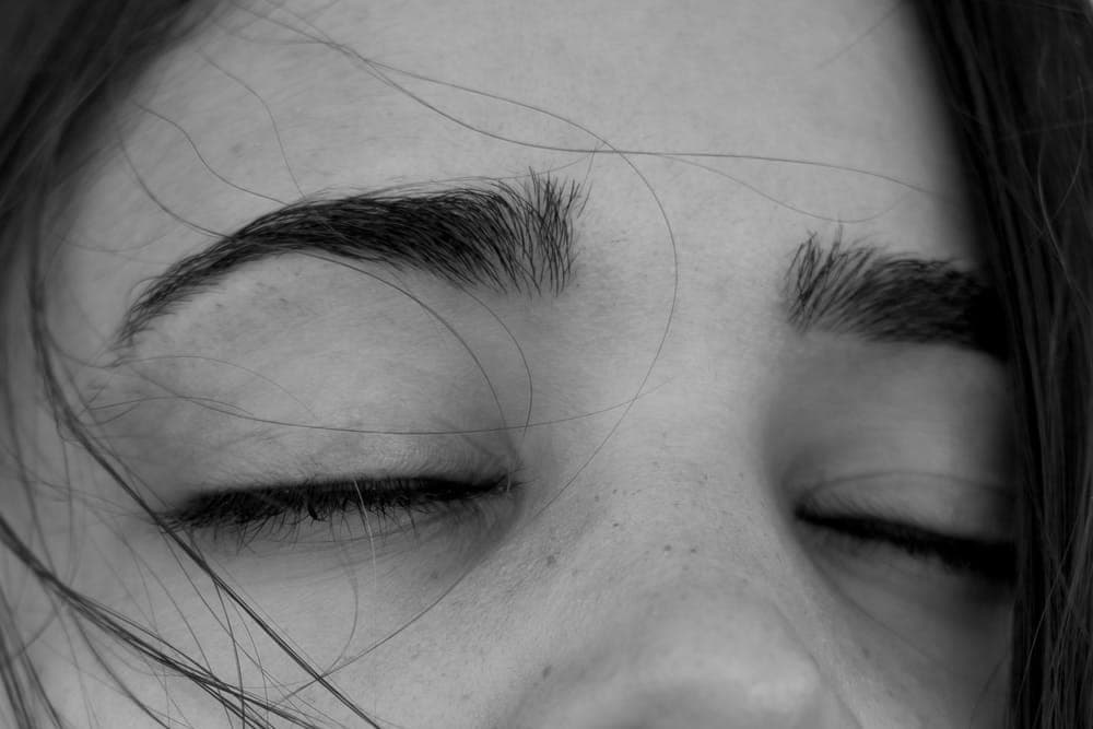 A close-up black-and-white photograph of a woman's face at rest